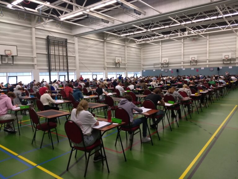 Een volle examenzaal met geconcentreerde leerlingen